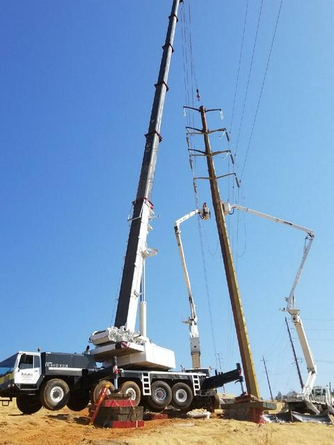 Our 200-ton all-terrain crane lifting high voltage towers on a steep grassy slope in Cameron Park, CA.
